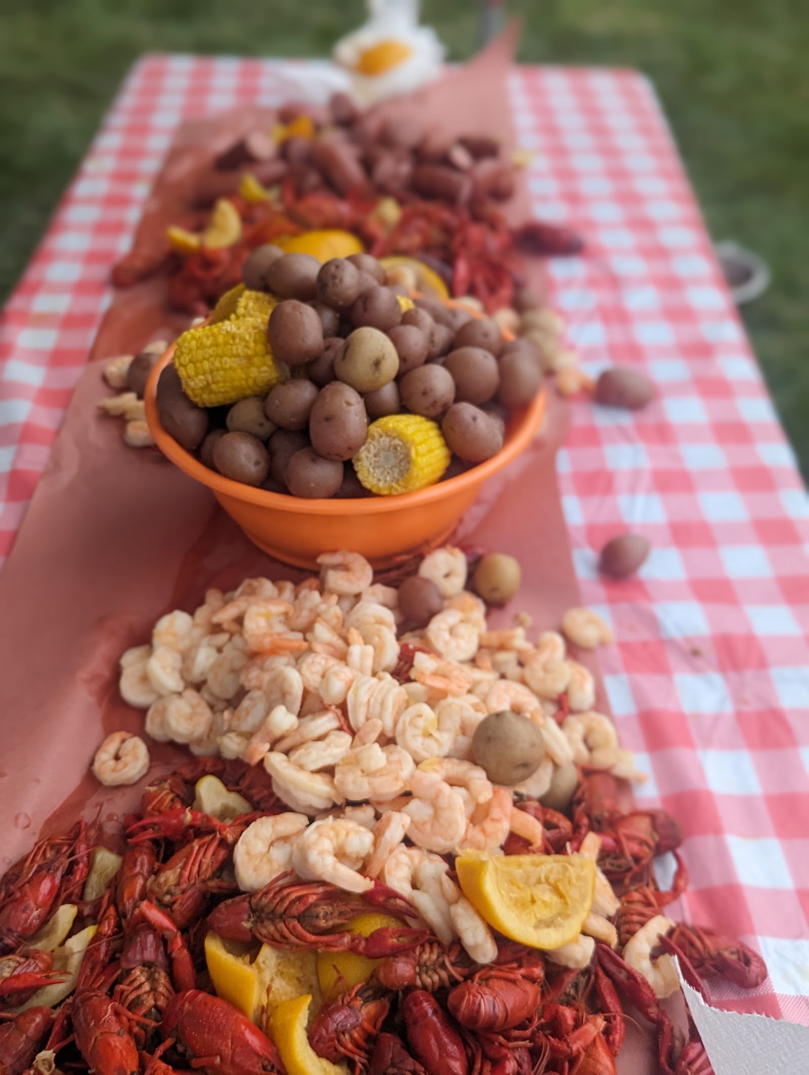 A heaping spread of crawfish, shrimp, corn and taters on a checkered tablecloth